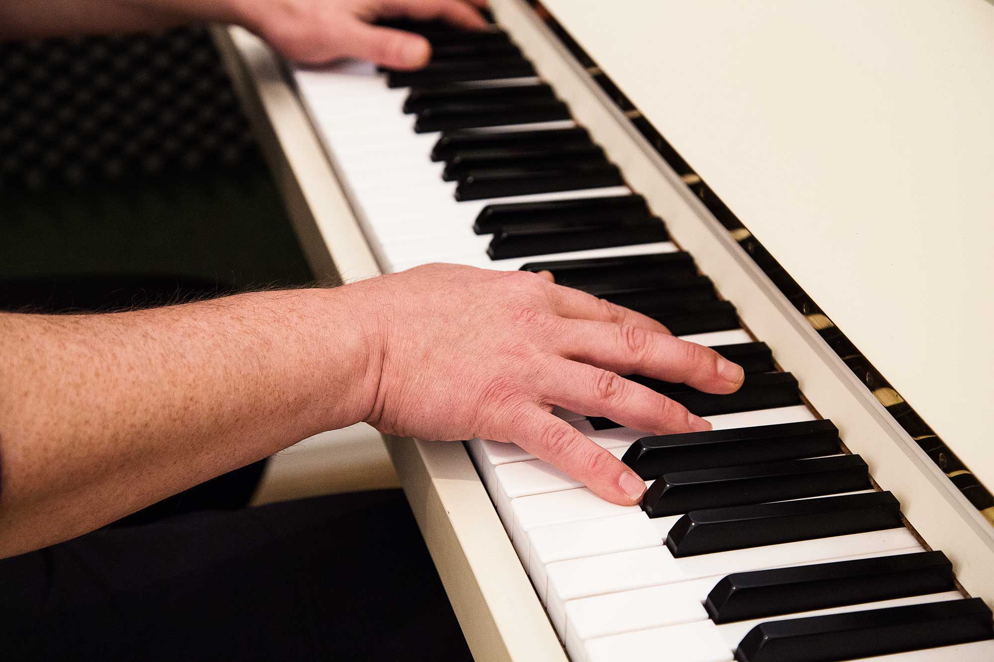 Haende spielen auf der Tastatur eines weissen Klaviers