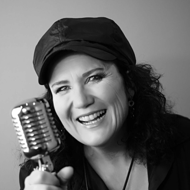 Claudia Schaefer - Claudia Schäfer, Sängerin und Vocaslcoach, hält ein Mikrofon in der rechten Hand