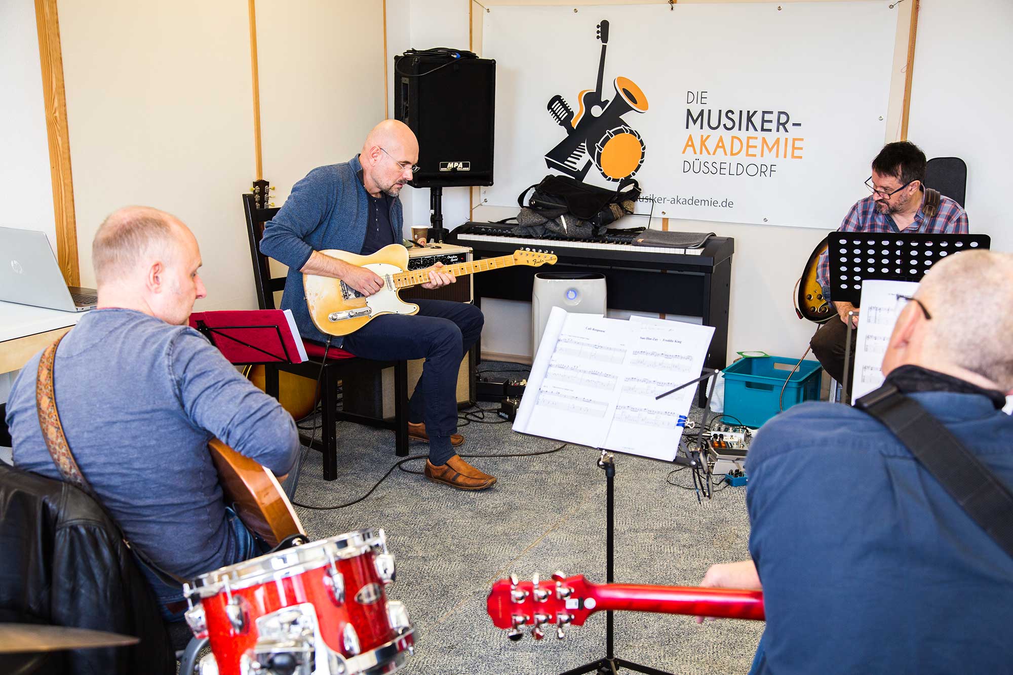 Gitarren-Dozent Jens Filser spielt Schuelern Blues-Licks auf der e-Gitarre vor.