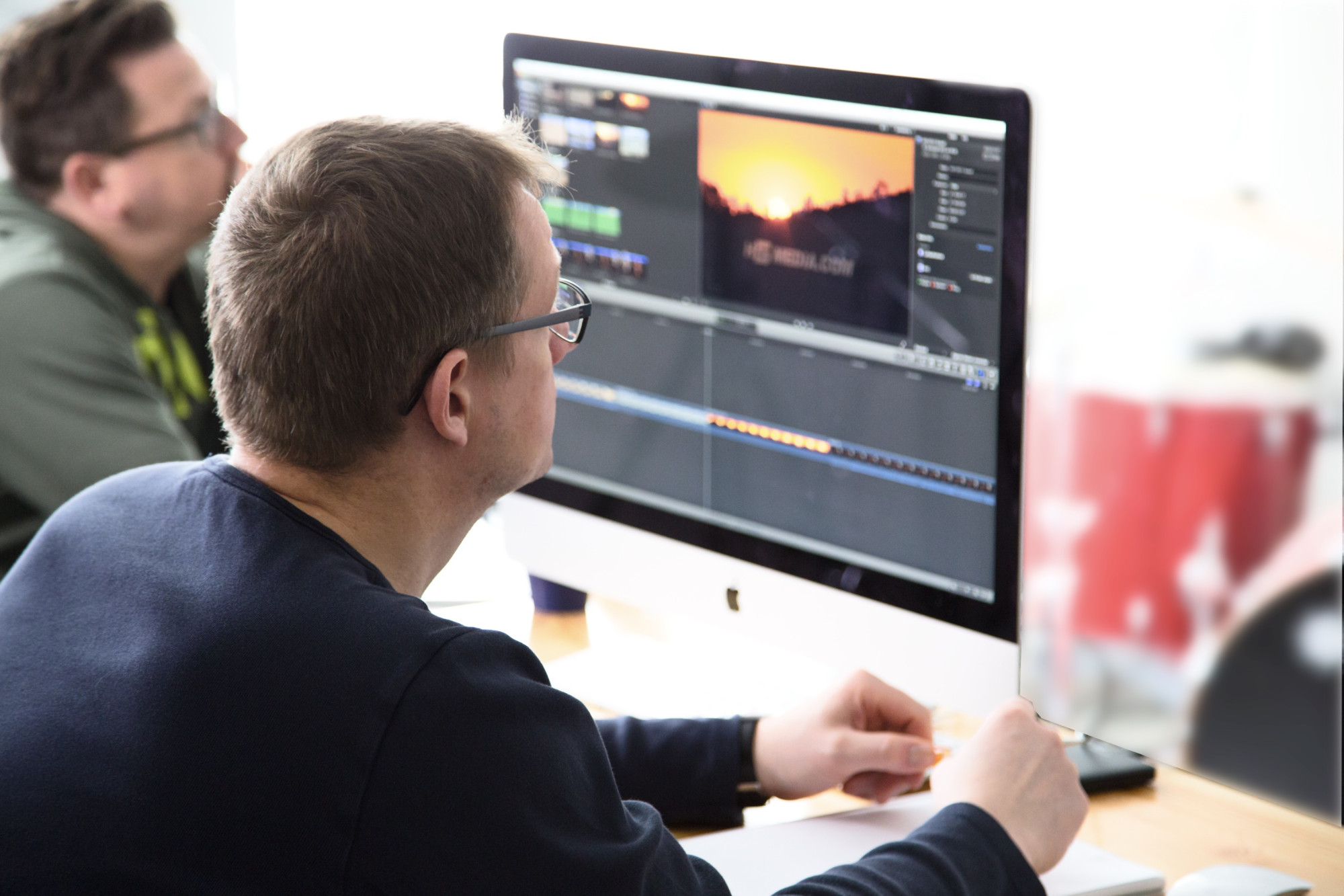 Ein Student sitzt vor einem Labtop-Monitor und bearbeitet einen Film mit Finalcut Pro X