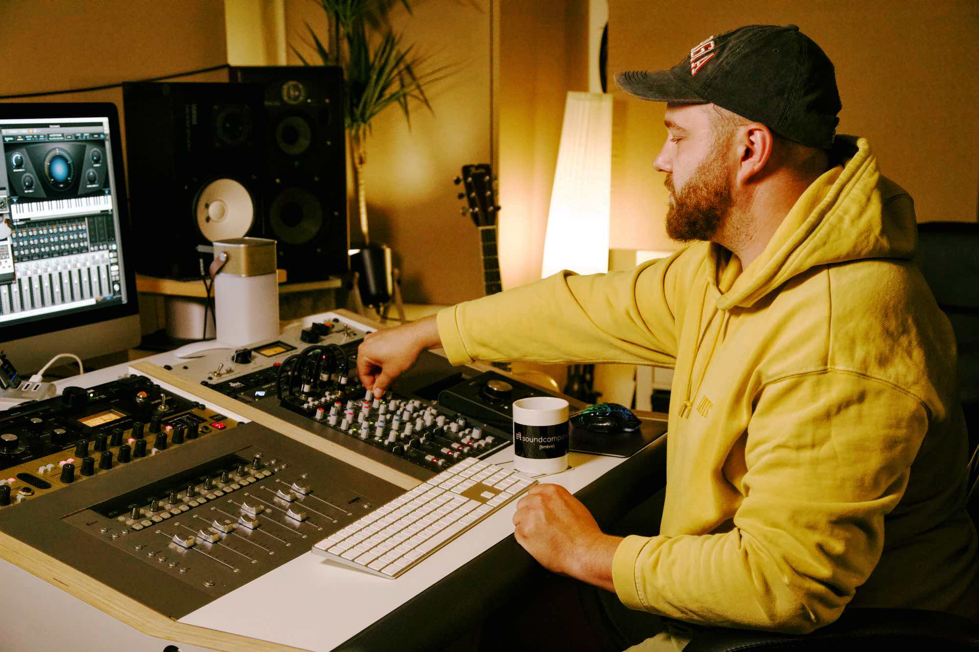 Tim Bremer sitzt vor einem Monitor und einem Mischpult und mischt einen Song mit Logic Pro X