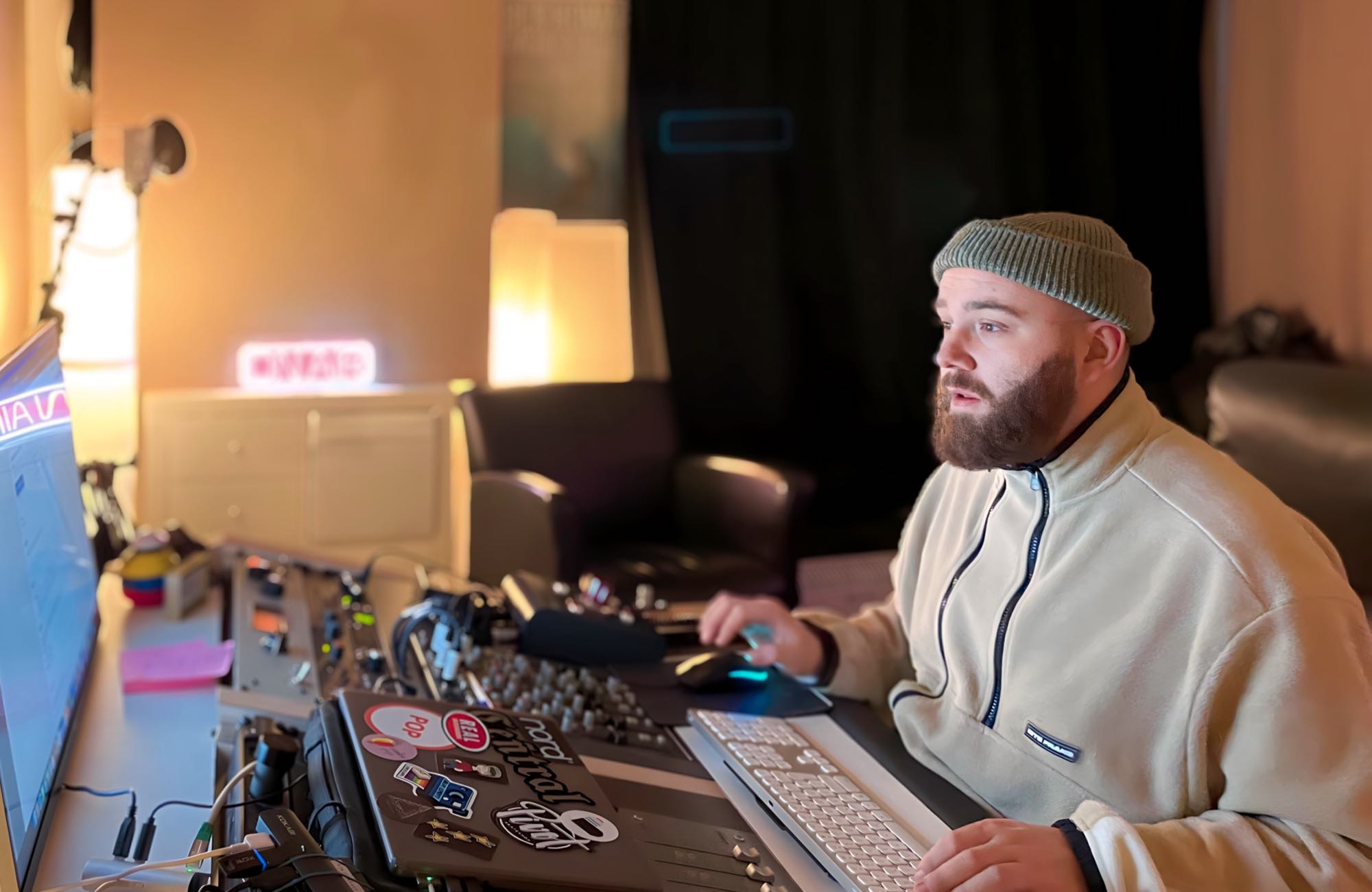 Tim Bremer sitzt vor einem Monitor und einem Mischpult und mischt einen Song mit Logic Pro X