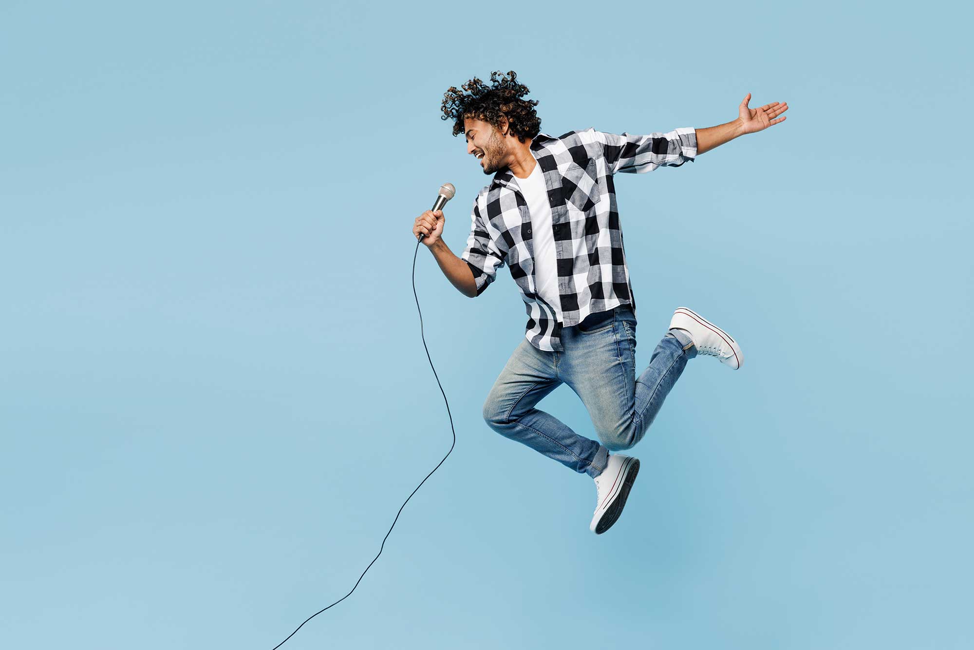 Ein Mann singt in ein Mikrofon und springt dabei in die Luft